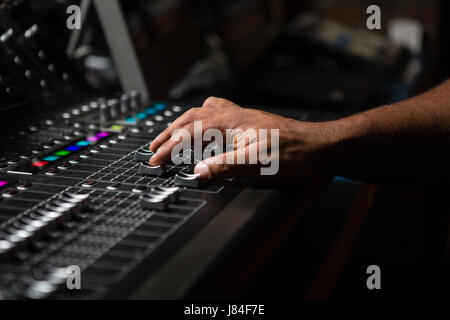 Hand of male audio engineer using sound mixer in recording studio Stock Photo
