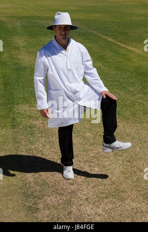 Portrait of cricket umpire signaling leg bye on field during match Stock Photo