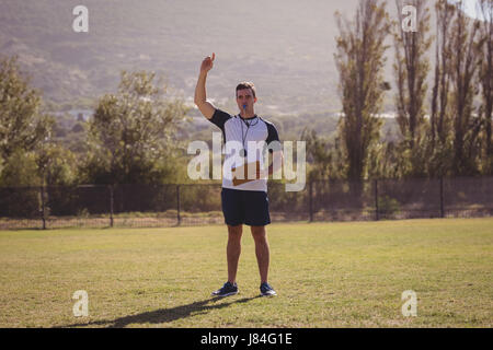 Coach blowing whistle during competition in park on a sunny day Stock Photo