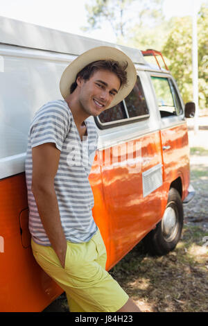 Portrait of man leaning on camper van in the park Stock Photo