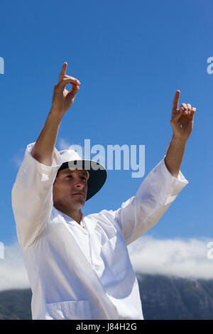 Low angle view of cricket umpire signalling six runs against blue sky during match on sunny day Stock Photo