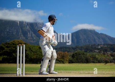 Full length of cricket player practicing against blue sky on field Stock Photo