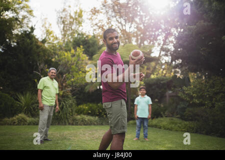Portrait of man playing rugby with family at park Stock Photo