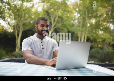 Smiling man using laptop on table at patio Stock Photo
