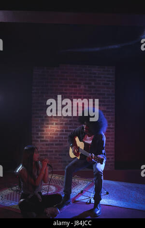Female singer with male guitarist practicing in nightclub Stock Photo