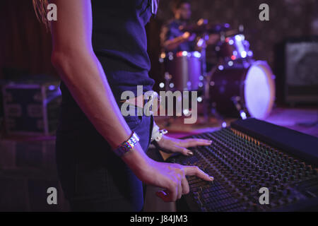 Mid section of female musician operating sound mixer in nightclub Stock Photo