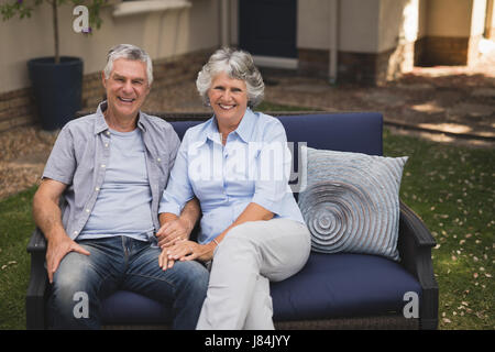 Portrait of happy senior couple sitting on couch in backyard Stock Photo
