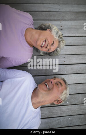 Overhead view of happy senior couple lying on wooden floor at porch Stock Photo