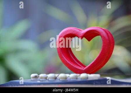 Red wood heart put on guitar for love on nature background Stock Photo