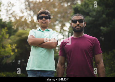 Confident father and son wearing sunglasses while standing at park Stock Photo
