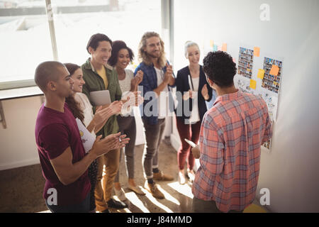 Team applauding while businessman discussing strategies at creative office Stock Photo