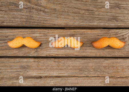 Close-up of baked cookies in mustache shape on wooden plank Stock Photo