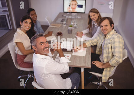Portrait of smiling business people attending video conference meeting in office Stock Photo