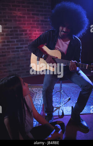 Female singer communicating with male guitarist while practicing in nightclub Stock Photo