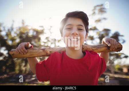 Portrait happy boy exercising with log during obstacle course in boot camp Stock Photo