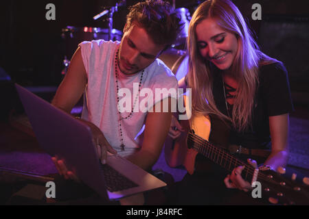 Male and female musicians using laptop while practicing in nightclub Stock Photo