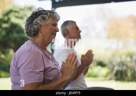 Side view of senior woman meditating with man meditating at porch Stock Photo