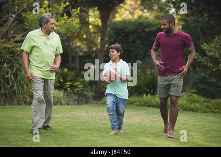 Boy with father and grandfather playing rugby at park Stock Photo