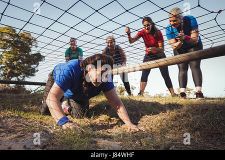 Woman being cheered bye her teammates during obstacle course training in the boot camp Stock Photo