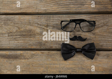 Overhead view of bow tie with mustache and eyeglasses on wooden table Stock Photo