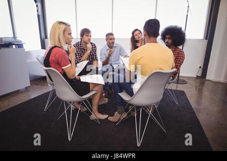 Serious business people disscussing plans while sitting in creative office Stock Photo