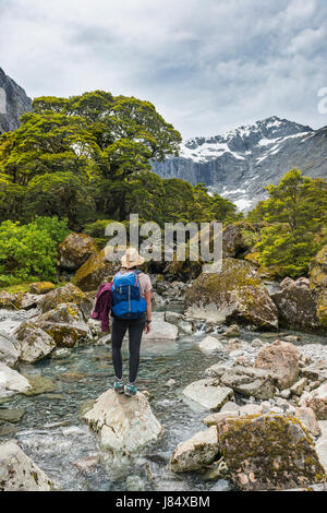 Female hiker on a rock in the river, Fiordland National Park, Southland, New Zealand Stock Photo