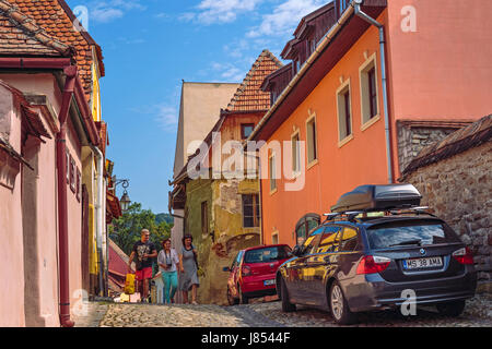 Sighisoara, Romania - July 26, 2014: Tourists stroll the narrow cobblestone streets in the historic center of Sighisoara. Stock Photo