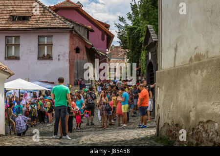 Sighisoara, Romania - July 26, 2014: Tourists stroll the old cobblestone streets in the medieval citadel of Sighisoara. Stock Photo