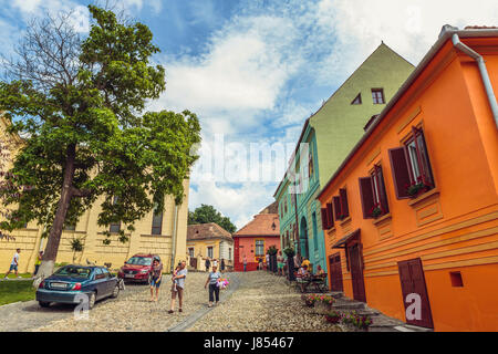 Sighisoara, Romania - July 26, 2014: Tourists stroll the old cobblestone streets in the medieval citadel of Sighisoara. Stock Photo