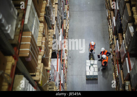 Group of workers in uniform and helmets having talk in aisle Stock Photo