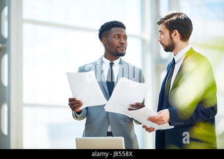 Two economists with papers having conversation Stock Photo