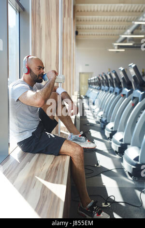 Thirsty man drinking water in gym after training Stock Photo