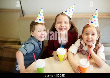 Adorable kids in birthday caps looking at camera Stock Photo