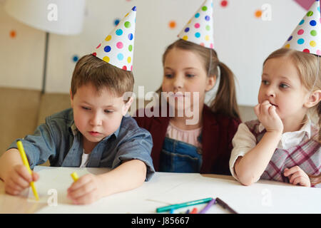 Creative kids in birthday caps drwaing with crayons Stock Photo