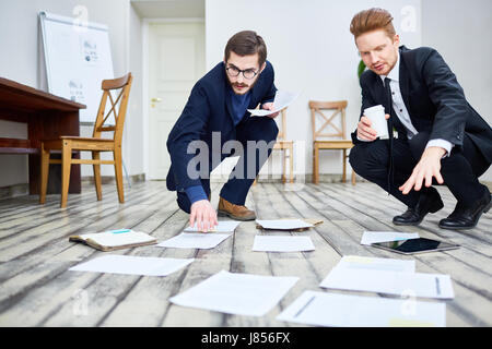 Portrait of two business men sorting documents on floor in office while working and making plans Stock Photo