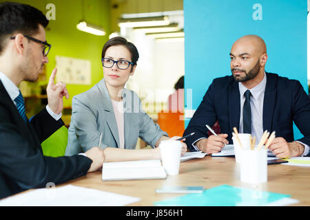 Portrait of three successful business people discussing work in colorful modern office Stock Photo