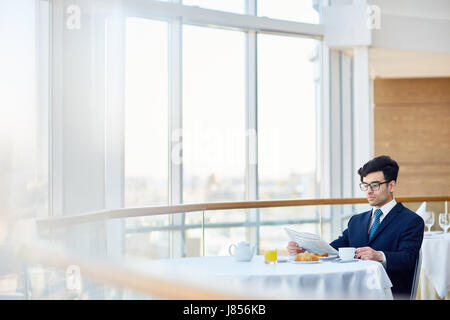 Serious man in suit sitting in cafe and reading news Stock Photo