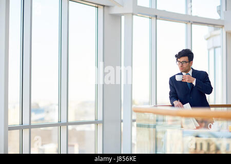 Pensive banker with cup of drink having coffee-break Stock Photo