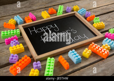 Close up of happy fathers day message on slate by toy blocks at table Stock Photo