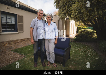 Portrait of smiling senior couple standing together against house in backyard Stock Photo
