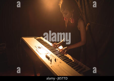 High angle view of female musician playing piano in illuminated nightclub Stock Photo