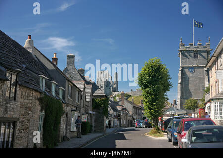 The castle, from West Street, Corfe Castle, Isle of Purbeck, Dorset, with, on the right, the parish church of St. Edward King and Martyr Stock Photo