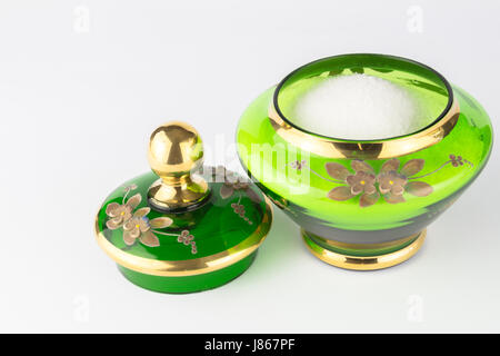 Green and gold vintage handcrafted sugar bowl full of sugar crystals and lid isolated on white background Stock Photo
