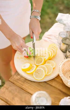 food, health, lifestyle, vegetarianism, cooking, nature concept - woman's hands with bright orange manicure, silver bracelet and wrist watch slice lemon and lime on white plate Stock Photo