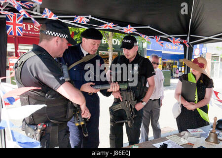 Lowestoft, UK. 24th May, 2017. Armed police officers, on patrol in Lowestoft town centre, take an interest in some wartime memorabilia including a fake incendiary device at a 1940s wartime stall. They chat with Ian Pycroft who, dressed as an air raid warden, was hosting one of the attractions at the Lowestoft 1940s Festival Weekend over the busy Spring Bank Holiday weekend in the UK. © Adrian Buck / Alamy Live News. Stock Photo