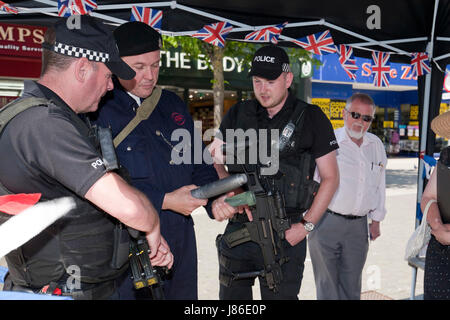 Lowestoft, UK. 24th May, 2017. Armed police officers, on patrol in Lowestoft town centre, take an interest in some wartime memorabilia including a fake incendiary device at a 1940s wartime stall. They chat with Ian Pycroft who, dressed as an air raid warden, was hosting one of the attractions at the Lowestoft 1940s Festival Weekend over the busy Spring Bank Holiday weekend in the UK. © Adrian Buck / Alamy Live News. Stock Photo