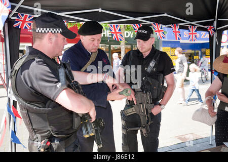 Lowestoft, UK. 24th May, 2017. Armed police officers, on patrol in Lowestoft town centre, take an interest in some wartime memorabilia including a fake incendiary device at a 1940s wartime stall. They chat with Ian Pycroft who, dressed as an air raid warden, was hosting one of the attractions at the Lowestoft 1940s Festival Weekend over the busy Spring Bank Holiday weekend in the UK. © Adrian Buck / Alamy Live News. Stock Photo