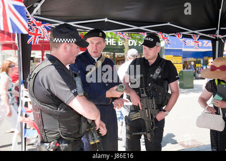 Lowestoft, UK. 24th May, 2017. Armed police officers, on patrol in Lowestoft town centre, take an interest in some wartime memorabilia including a fake incendiary device at a 1940s wartime stall. They chat with Ian Pycroft who, dressed as an air raid warden, was hosting one of the attractions at the Lowestoft 1940s Festival Weekend over the busy Spring Bank Holiday weekend in the UK. © Adrian Buck / Alamy Live News. Stock Photo