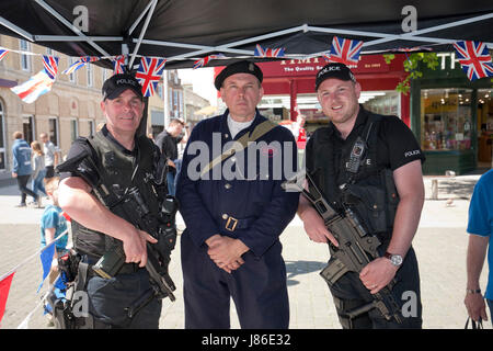 Lowestoft, UK. 24th May, 2017. Armed police officers pose with Norfolk historic event organiser Ian Pycroft at his 1940s wartime stall in Lowestoft. Dressed as an air raid warden, Mr. Pycroft hosted one of the attractions at Lowestoft's 1940s festival over the busy Spring Bank Holiday weekend in the UK. © Adrian Buck / Alamy Live News. Stock Photo