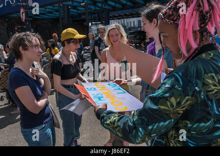 London, UK. 27th May 2017. Sisters look at a poster 'THis is Community Land' about ther former Hollway Prison as North London Sisters Uncut meet at Camden Rd station for their 'general election rally' in a protest against Tory budgets that have cut support for refuges for victims of domestic violence. After I left they marched to the now disused Holloway Prison, occupying the former visitors centre.  The intend to hold a week of workshops on women’s well being, self-defence and legal rights there before leaving. They say the former women's prison is public land and should be used for public go Stock Photo
